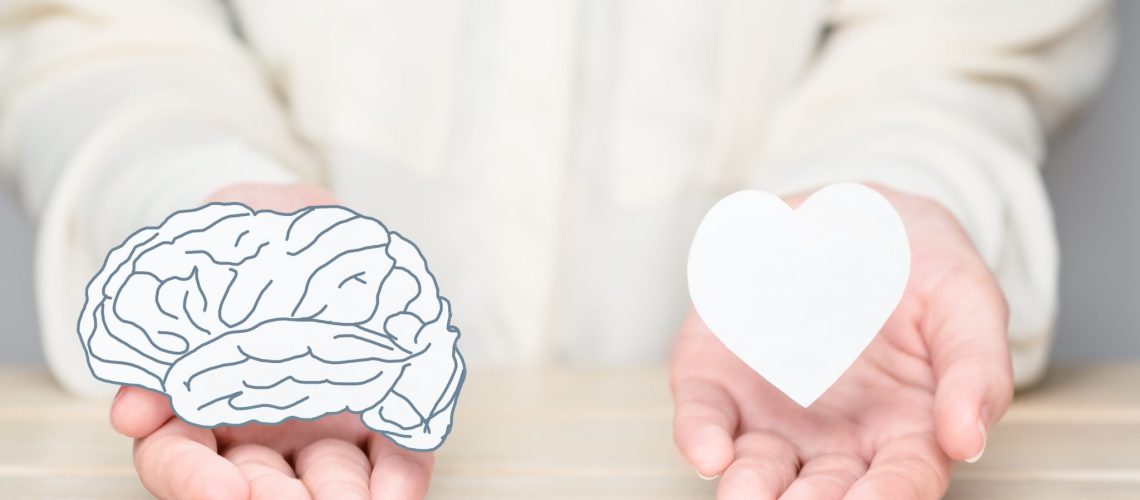 Female hands holding paper cut brain and soul. Conflict between emotions and rational thinking. Balance and equilibrium between mind and heart concept.